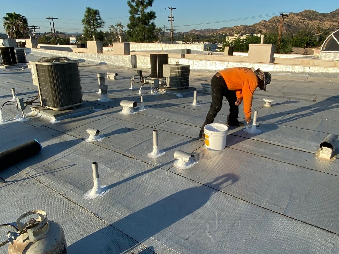 Worker applying sealant on a rooftop.